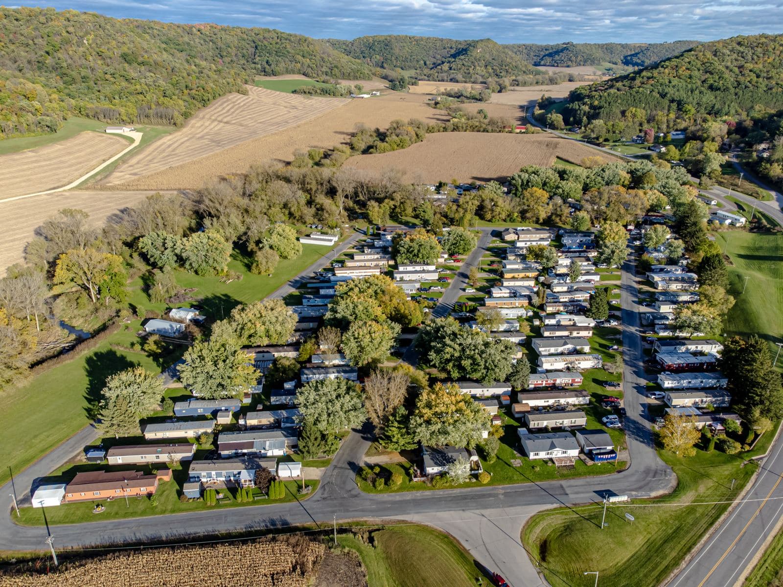 Aerial view of a tidy land-lease manufactured home community among trees